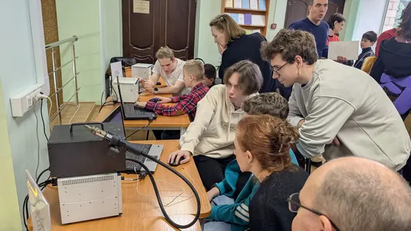 Подростки и взрослые смотрят, как работает паяльная станция